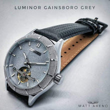 Load image into Gallery viewer, The Luminor Series was conceived with the idea of bold illumination of the digits and hands on a minimalistic watch face. Our first model in this series is featuring a matt grey casing, exquisite black genuine leather strap, bold luminous green digits and hands and a matt grey finish on the dial. We manufacture this watch under the control and supervision of our experienced and skilled watchmakers in our own workshop.