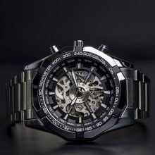 Load image into Gallery viewer, Elements with its raw metallic skeleton design is a magnetic timepiece for the modern gentleman. Equipped with stainless steel case and strap and a black and silver metallic face to give this timepiece its solid masculine character. Features include hour, minute, second, date and month indicators and an automatic mechanical chronometer with a 48-hour power reserve. 
